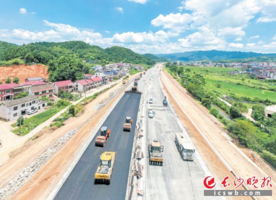 运料车、摊铺机、压路机等有序作业,沥青路面慢慢成形。